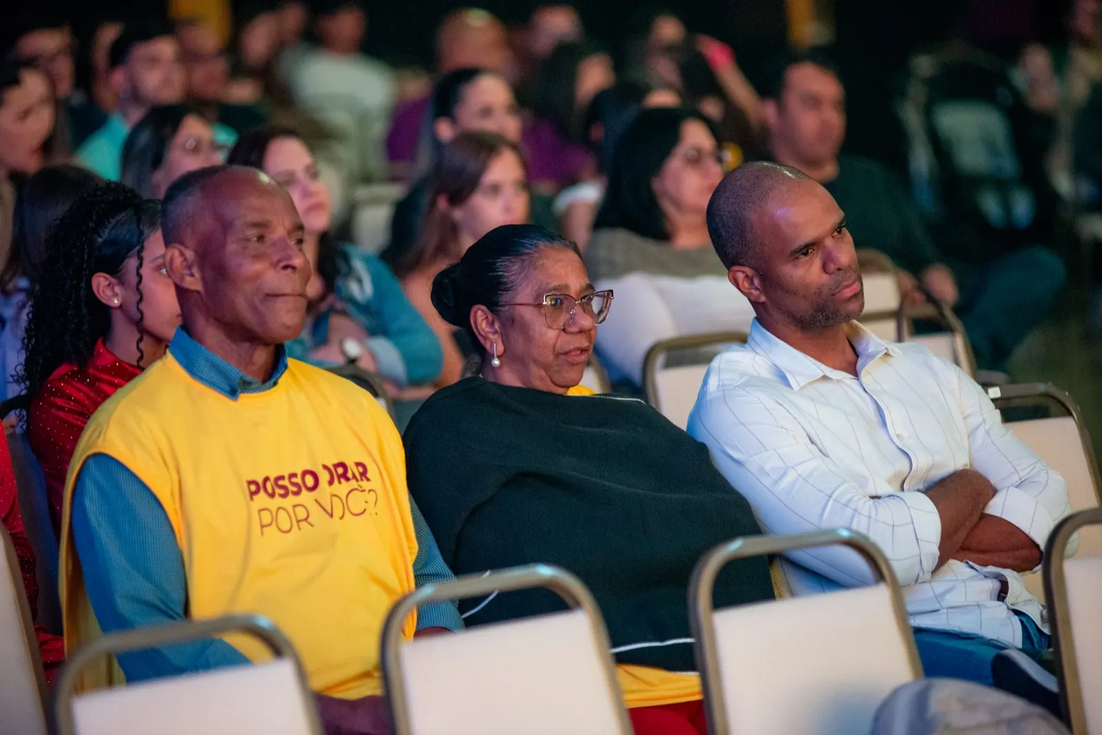 Três pessoas sentadas assistindo à programação