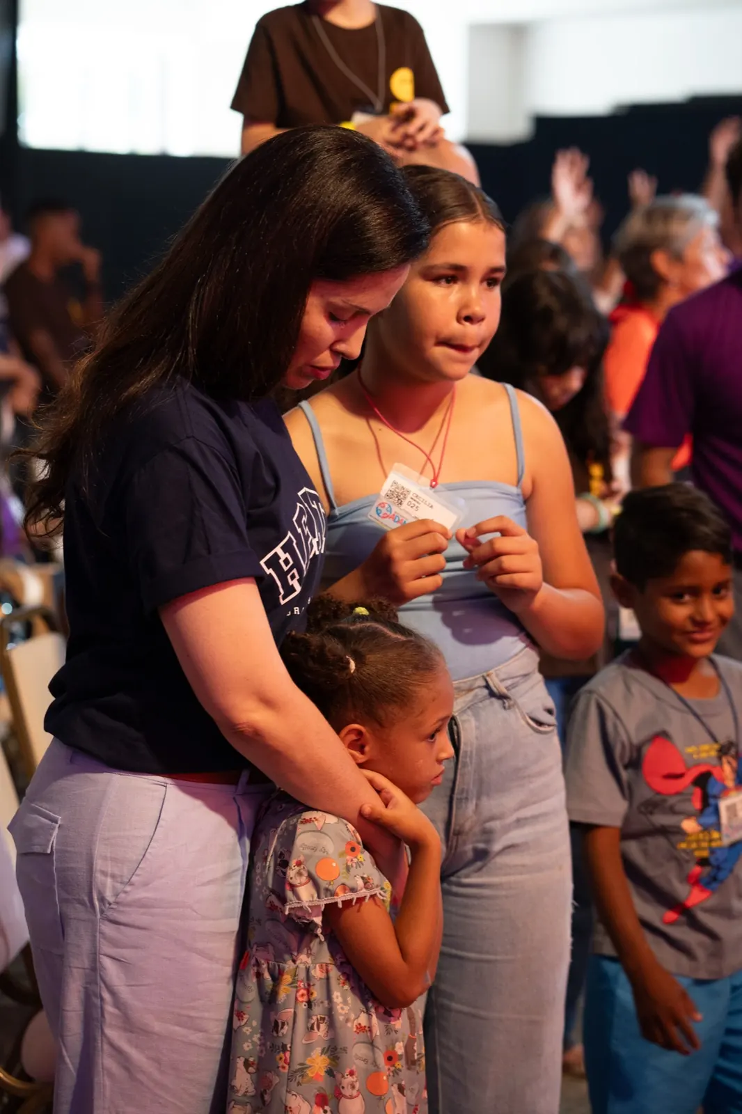 Adulta abraçando duas crianças durante a oração